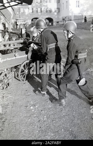 Eine Gruppe von der Kinderfeuerwehr mit dem Löschwagen bei einer Feuerwehrübung, Deutschland 1930er Jahre. Eine Gruppe von Junior Feuerwehrmänner ist die Vorbereitung der firewagon während ein Feuerwehrmann, Deutschland 1930. Stockfoto