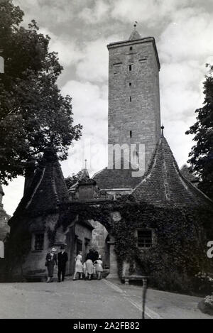 Passanten durchqueren das Burgtor mit dem großem Torturm in Rothenburg o.d. Tauber, Deutschland 1930er Jahre. Fußgänger das Burgtor mit dem großen Turm in Rothenburg o.d. Tauber, Deutschland 1930. Stockfoto