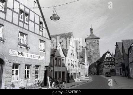 Eine Pflastersteingasse, sterben vorbei eine Fachwerkhäusern und alten Kutschen zum Sieberstor in Rohenburg o.d. Tauber führt, Deutschland 1930er Jahre. Ein Pflasterstein Gasse, die in Richtung der Sieberstor/Siebers Tor in Rothenburg o.d. Tauber, vorbei an alten Wagen und Fachwerkhäusern, Deutschland 1930. Stockfoto