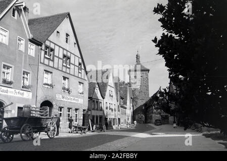 Eine Pflastersteingasse, sterben vorbei eine Fachwerkhäusern und alten Kutschen zum Sieberstor in Rohenburg o.d. Tauber führt, Deutschland 1930er Jahre. Ein Pflasterstein Gasse, die in Richtung der Sieberstor/Siebers Tor in Rothenburg o.d. Tauber, vorbei an alten Wagen und Fachwerkhäusern, Deutschland 1930. Stockfoto