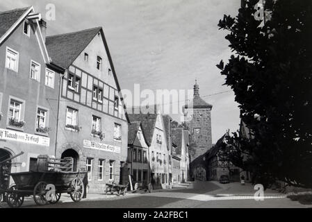 Eine Pflastersteingasse, sterben vorbei eine Fachwerkhäusern und alten Kutschen zum Sieberstor in Rohenburg o.d. Tauber führt, Deutschland 1930er Jahre. Ein Pflasterstein Gasse, die in Richtung der Sieberstor/Siebers Tor in Rothenburg o.d. Tauber, vorbei an alten Wagen und Fachwerkhäusern, Deutschland 1930. Stockfoto