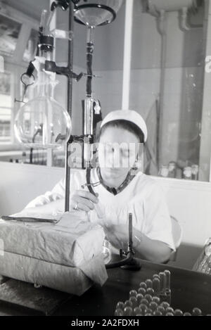 Eine Laborantin fertigt in Arbeit der Behringwerke Proben eines Medikaments ein, Marburg, Deutschland 1930er Jahre. Eine Lab Assistant ist die Einnahme von Medikamenten Proben im Labor der Behringwerke, Marburg, Deutschland 1930. Stockfoto