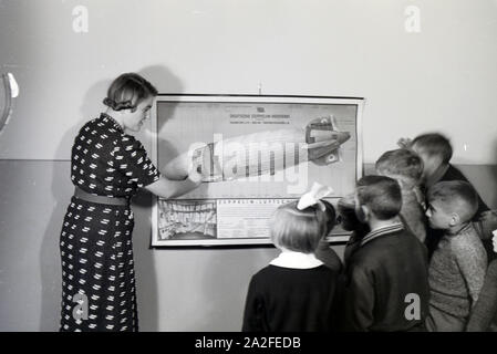 Eine Schulklasse lässt sich mit großem Interesse von ihrer Lehrerin den Aufbau eines Zeppeline erklären, Zeppelin Siedlung bei Frankfurt am Main, Deutschland 1930er. Ein Lehrer erklärt den Bau einer zeppelinl zu ihrer Schüler, die Hören mit großem Interesse sind, zeppelin Dorf in der Nähe von Frankfurt am Main, Deutschland 1930. Stockfoto