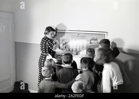 Eine Schulklasse lässt sich mit großem Interesse von ihrer Lehrerin den Aufbau eines Zeppeline erklären, Zeppelin Siedlung bei Frankfurt am Main, Deutschland 1930er. Ein Lehrer erklärt den Bau einer zeppelinl zu ihrer Schüler, die Hören mit großem Interesse sind, zeppelin Dorf in der Nähe von Frankfurt am Main, Deutschland 1930. Stockfoto