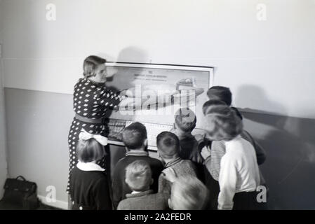 Eine Schulklasse lässt sich mit großem Interesse von ihrer Lehrerin den Aufbau eines Zeppeline erklären, Zeppelin Siedlung bei Frankfurt am Main, Deutschland 1930er. Ein Lehrer erklärt den Bau einer zeppelinl zu ihrer Schüler, die Hören mit großem Interesse sind, zeppelin Dorf in der Nähe von Frankfurt am Main, Deutschland 1930. Stockfoto