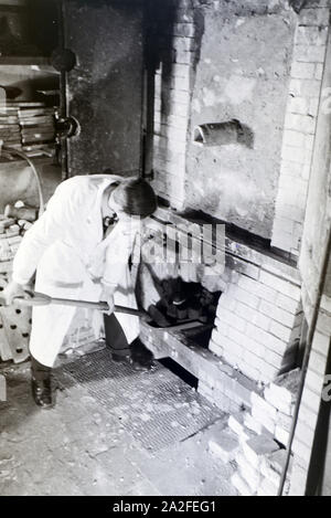 Ein Schüler der Fachschule für Keramik stellt frisch getöpferte Gefäße in den Brennofen, Höhr-Grenzhausen, Deutschland 1930er Jahre. Ein Student der Hochschule für Keramik setzt neu Töpfe in den Brennofen, Höhr-Grenzhausen, Deutschland 1930 fictiled. Stockfoto