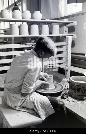 Ein Schüler der Fachschule für Keramik bei der Arbeit an der Töpferscheibe in der Höhle Arbeitsateliers, Höhr-Grenzhausen, Deutschland 1930er Jahre. Ein Student der Hochschule für Keramik der Töpferei Rad in die Ateliers arbeiten, Höhr-Grenzhausen, Deutschland 1930. Stockfoto