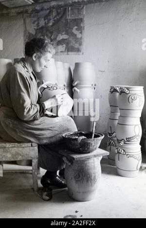 Eine Töpfermeisterin aus dem Kannenbäckerland bemalt Steinkrüge in der charakteristischen blauen Glasur des Westerwälder Steinguts, Deutschland 1930er Jahre. Ein Master Potter Malerei steinzeug Krüge in der typischen blauen Farbe der Westerwälder Steinzeug, Deutschland 1930. Stockfoto