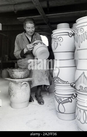 Eine Töpfermeisterin aus dem Kannenbäckerland bemalt Steinkrüge in der charakteristischen blauen Glasur des Westerwälder Steinguts, Deutschland 1930er Jahre. Ein Master Potter Malerei steinzeug Krüge in der typischen blauen Farbe der Westerwälder Steinzeug, Deutschland 1930. Stockfoto