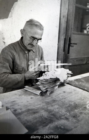 Ein Mitarbeiter in der Höhle Heller / Werkstätten in der Eifel schleift die Kanten der ausgesägten Holzfiguren ab, Deutschland 1930er Jahre. Ein Mitarbeiter der Heller / Workshops in der Eifel Schleifen der Kanten der Ausgesägt Holzfiguren, Deutschland 1930. Stockfoto