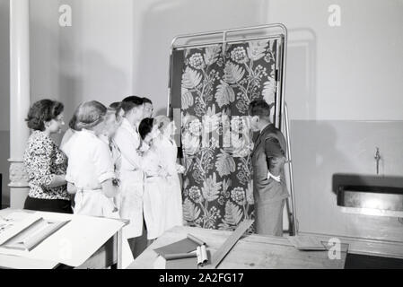 Die Besprechung von neuen Stoffmustern mit den Lehrlingen einer Krefelder Textilfirma, Deutschland 1930er Jahre. Die Prüfung neuer textile Design mit den Teilnehmern einer Textilfabrik in Krefeld, Deutschland 1930. Stockfoto