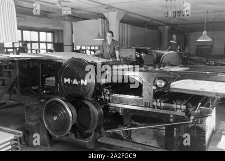 Eine Arbeiterin Rotationsdruckmaschine kontrolliert Sterben in den Werken des Maschinenbaukonzerns MAN (Maschinenfabrik Augsburg-Nürnberg), Deutschland 1930er Jahre. Ein Arbeitnehmer, der die Steuerung der Rotationsdruckmaschine, die in den Anlagen der mechanischen Engineering Company MAN (Maschinenfabrik Augsburg-Nürnberg), Deutschland 1930. Stockfoto