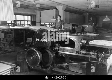 Eine Arbeiterin Rotationsdruckmaschine kontrolliert Sterben in den Werken des Maschinenbaukonzerns MAN (Maschinenfabrik Augsburg-Nürnberg), Deutschland 1930er Jahre. Ein Arbeitnehmer, der die Steuerung der Rotationsdruckmaschine, die in den Anlagen der mechanischen Engineering Company MAN (Maschinenfabrik Augsburg-Nürnberg), Deutschland 1930. Stockfoto