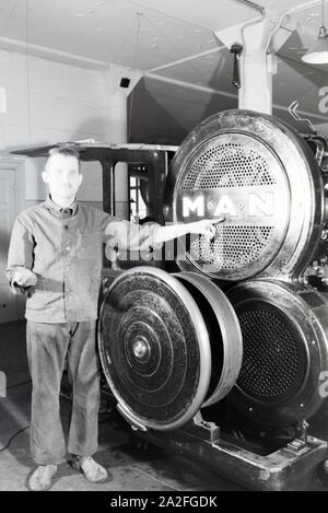 Ein Arbeiter posiert vor einer Rotationsdruckmaschine in den Werken des Maschinenbaukonzerns MAN (Maschinenfabrik Augsburg-Nürnberg), Deutschland 1930er Jahre. Ein Arbeitnehmer vor einer Rotationsdruckmaschine posieren in den Anlagen der mechanischen Engineering Company MAN (Maschinenfabrik Augsburg-Nürnberg), Deutschland 1930. Stockfoto