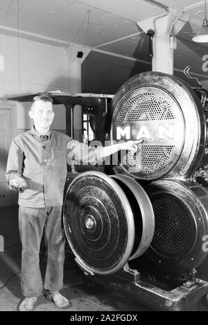 Ein Arbeiter posiert vor einer Rotationsdruckmaschine in den Werken des Maschinenbaukonzerns MAN (Maschinenfabrik Augsburg-Nürnberg), Deutschland 1930er Jahre. Ein Arbeitnehmer vor einer Rotationsdruckmaschine posieren in den Anlagen der mechanischen Engineering Company MAN (Maschinenfabrik Augsburg-Nürnberg), Deutschland 1930. Stockfoto