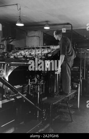 Ein Drucker kontrolliert sterben Rotationsdruckmaschine in den Werken des Maschinenbaukonzerns MAN (Maschinenfabrik Augsburg-Nürnberg), Deutschland 1930er Jahre. Einen Drucker steuern der Rotationsdruckmaschine, die in den Anlagen der mechanischen Engineering Company MAN (Maschinenfabrik Augsburg-Nürnberg), Deutschland 1930. Stockfoto