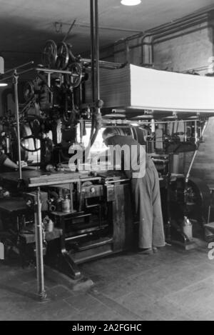 Ein Drucker setzt Lettern zu einem Schriftstatz Eine einer Rotationsdruckmaschine zusammen, Deutschland 1930er Jahre. Ein Drucker ist die Anordnung aus Metall Art auf einer Rotationsdruckmaschine, Deutschland 1930. Stockfoto