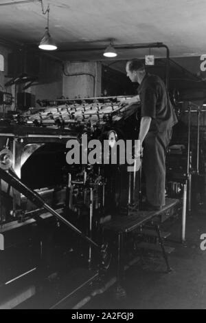 Ein Drucker kontrolliert sterben Rotationsdruckmaschine in den Werken des Maschinenbaukonzerns MAN (Maschinenfabrik Augsburg-Nürnberg), Deutschland 1930er Jahre. Einen Drucker steuern der Rotationsdruckmaschine, die in den Anlagen der mechanischen Engineering Company MAN (Maschinenfabrik Augsburg-Nürnberg), Deutschland 1930. Stockfoto