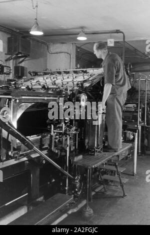 Ein Drucker kontrolliert sterben Rotationsdruckmaschine in den Werken des Maschinenbaukonzerns MAN (Maschinenfabrik Augsburg-Nürnberg), Deutschland 1930er Jahre. Einen Drucker steuern der Rotationsdruckmaschine, die in den Anlagen der mechanischen Engineering Company MAN (Maschinenfabrik Augsburg-Nürnberg), Deutschland 1930. Stockfoto