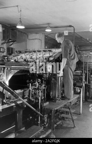 Ein Drucker kontrolliert sterben Rotationsdruckmaschine in den Werken des Maschinenbaukonzerns MAN (Maschinenfabrik Augsburg-Nürnberg), Deutschland 1930er Jahre. Einen Drucker steuern der Rotationsdruckmaschine, die in den Anlagen der mechanischen Engineering Company MAN (Maschinenfabrik Augsburg-Nürnberg), Deutschland 1930. Stockfoto