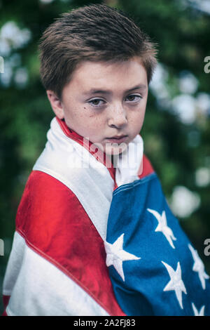 Wenig gemischten Rennen asiatischen Kaukasischen brünette Junge in der amerikanischen Flagge mit ernsten traurigen Gesichtsausdruck Stirnrunzeln gewickelt Stockfoto