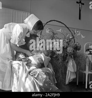 Neuankömmling Auf der Geburtsstation des Rotkreuzkrankenhauses München, 1930er Jahre Deutschland. Neues Baby geboren mit Großmutter und Krankenschwester bei der Neugeborenen-Station des Roten Kreuz Krankenhauses München der 1930er Jahre. Stockfoto