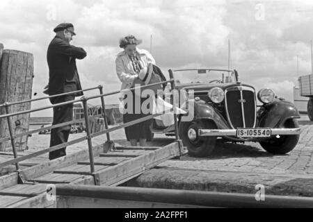 Eine Frau begrüßt einen Seemann an der Gangway in Norddeich Mole vor ihrem Audi Cabrio, Deutschland 1930er Jahre. Eine Frau und ein Seemann die Hände schütteln über einen Gang vor ein Audi Cabrio, Deutschland 1930. Stockfoto