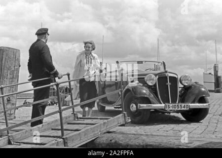 Eine Frau begrüßt einen Seemann an der Gangway in Norddeich Mole vor ihrem Audi Cabrio, Deutschland 1930er Jahre. Eine Frau und ein Seemann die Hände schütteln über einen Gang vor ein Audi Cabrio, Deutschland 1930. Stockfoto