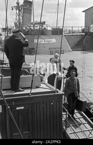 Fahrgäste werden vom Classic-car salutierend begrüßt an der Mole in Norddeich, Deutschland 1930er Jahre. Die Passagiere werden Grüßte durch den Kapitän an der Pier in Norddeich, Deutschland 1930. Stockfoto