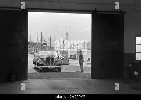 Eine Frau fährt ihr Audi Cabrio in eine der Garagen am Meer in Norddeich, Deutschland 1930er Jahre. Eine Frau, die ihrem Audi convertibel in einer der Garagen bei Norddeich, Deutschland 1930. Stockfoto