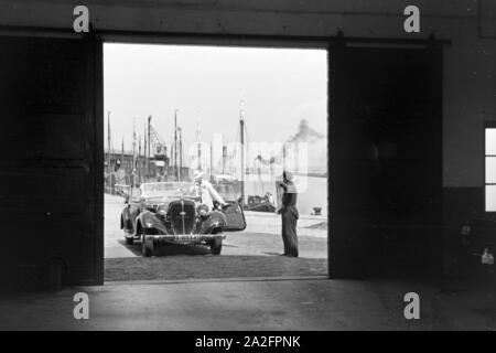 Eine Frau fährt ihr Audi Cabrio in eine der Garagen am Meer in Norddeich, Deutschland 1930er Jahre. Eine Frau, die ihrem Audi convertibel in einer der Garagen bei Norddeich, Deutschland 1930. Stockfoto