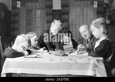 Mitglieder einer kinderreichen Familie bei den Hausaufgaben, Deutsches Reich 30er Jahre. Mitglieder einer Großfamilie, die Hausaufgaben, Deutschland 1930. Stockfoto