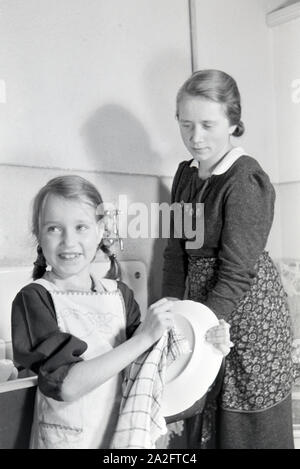 Mitglieder einer kinderreichen Familie bei der Hausarbeit, Deutsches Reich 30er Jahre. Mitglieder einer Großfamilie, die die Hausarbeit, Deutschland 1930. Stockfoto