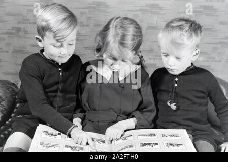 Mitglieder einer kinderreichen Familie schulmeisterschaft sich gemeinsam ein Fotoalbum ein, Deutsches Reich 30er Jahre. Mitglieder einer Großfamilie zu einem Fotoalbum suchen, Deutschland 1930. Stockfoto