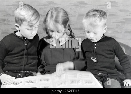 Mitglieder einer kinderreichen Familie schulmeisterschaft sich gemeinsam ein Fotoalbum ein, Deutsches Reich 30er Jahre. Mitglieder einer Großfamilie zu einem Fotoalbum suchen, Deutschland 1930. Stockfoto