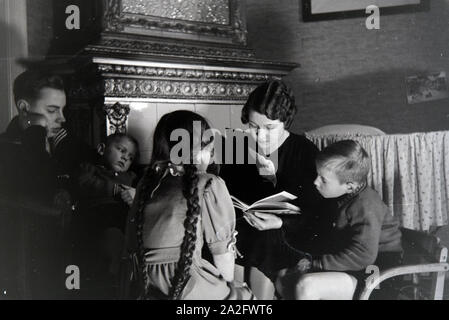 Mitglieder einer kinderreichen Familie lesen gemeinsam ein Buch, Deutsches Reich 30er Jahre. Mitglieder einer Großfamilie zusammen ein Buch lesen, Deutschland 1930. Stockfoto