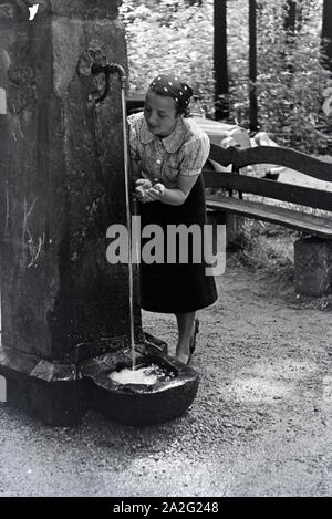 Eine junge Frau probiert das Trinkwasser des Eberbrunnens auf einem Wanderpfad bei Baden-Baden im Nordschwarzwald, Deutschland 1930er Jahre. Eine junge w Stockfoto