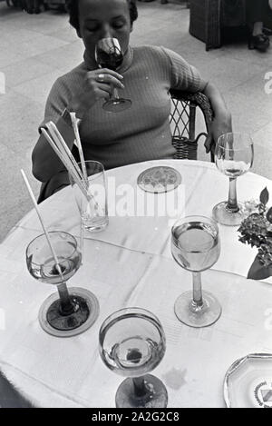 Eine junge Frau probiert ein Getränk im Restaurant des Kurhauscasinos in Baden-Baden, Deutschland, 1930er Jahre. Eine junge Frau schmeckt ein Getränk im Restaurant im Kurhaus Casino Baden-Baden, Deutschland 1930. Stockfoto