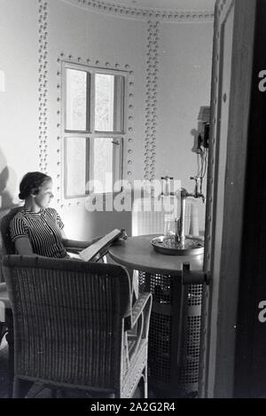 Eine junge Frau entspannt bei der Zeitschriftlektüre im Ruheraum bei Ihrem 206 der Caracalla Thermen in Baden-Baden, Deutschland, 1930er Jahre. Eine junge Frau bei einem Magazin im Ruheraum, bei ihrem Besuch der Caracalla Therme in Baden-Baden, Deutschland 1930. Stockfoto