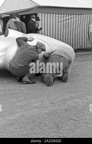 Mechaniker überprüfen die Stromlinienverkleidung des Mercedes Benz W 125 vor dem Start zum Weltrekordversuch, Deutschland 1930er Jahre. Mechanik prüfen die Stromlinienform des Mercedes Benz W 125 vor dem Start in den Weltrekord Versuch, Deutschland 1930. Stockfoto