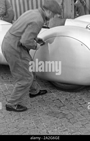 Ein Mechaniker überprüft vor dem Start zum Weltekordversuch den Mercedes Benz W125, Deutschland 1930er Jahre. Eine mechanische Kontrolle des Mercedes Benz W 125 vor dem Start in den Weltrekord Versuch, Deutschland 1930. Stockfoto