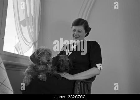 Eine Frau mit zwei Dackeln in ihrem Zimmer im Schlosshotel in Oberhof in Thüringen, Deutschland 1930er Jahre. Eine Frau und zwei dachshounds Ihr Doppelzimmer im Schlosshotel Hotel in Oberhof in Thüringen, Deutschland 1930. Stockfoto