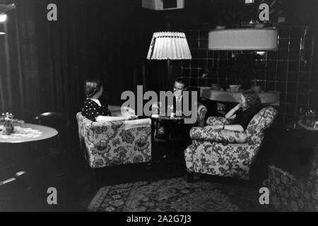 Gäste im Kaminzimmer im Schlosshotel in Oberhof in Thüringen, Deutschland 1930er Jahre. Gäste können sich am Kamin im Schlosshotel hotel Sitze in Oberhof in Thüringen, Deutschland 1930. Stockfoto