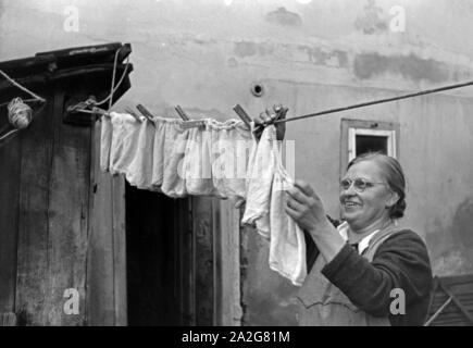 Die Großmutter macht die Wäsche und Knipser Vierlinge, Deutschland 1930er Jahre. Großmutter ist das Waschen von quadruplet Mädchen Knipser, Deutschland 1930. Stockfoto