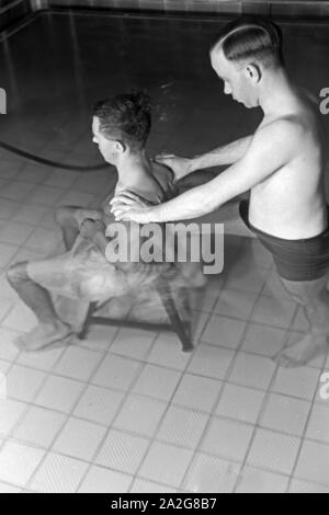 Ein Patient bei der Unterwasserbehandlung mit einem Bademeister, Deutschland 1930er Jahre. Ein Patient in einem Heilbad, Deutschland 1930. Stockfoto