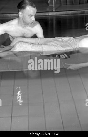 Ein Patient bei der Unterwasserbehandlung mit einem Bademeister, Deutschland 1930er Jahre. Ein Patient in einem Heilbad, Deutschland 1930. Stockfoto