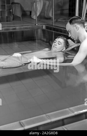 Ein Patient bei der Unterwasserbehandlung mit einem Bademeister, Deutschland 1930er Jahre. Ein Patient in einem Heilbad, Deutschland 1930. Stockfoto