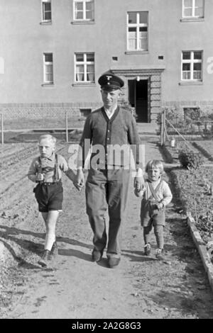 Ein Mann kommt mit zwei kleinen Kindern an der Hand aus einem Haus auf der Halbinsel Hela in Ostpreußen, Deutschland 1930er Jahre. Ein Mann mit zwei kleinen Kindern auf seinen Händen aus einem Haus an der Hela in Ostpreußen, Deutschland 1930. Stockfoto