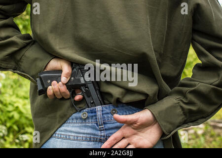 Die junge Frau hält das Gewehr hinter ihr zurück in seine Hand. Stockfoto