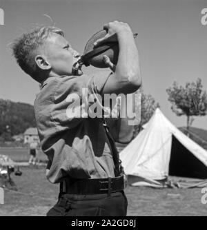 Durstiger Hitlerjunge trinkt aus thunfischwadenfänger Feldflasche im Hitlerjugend Lagerbier, Österreich 1930er Jahre. Durstig Hitle Jugend dirnking aus seiner Wasserflasche an die Hitler Jugend Camp, Österreich 1930. Stockfoto